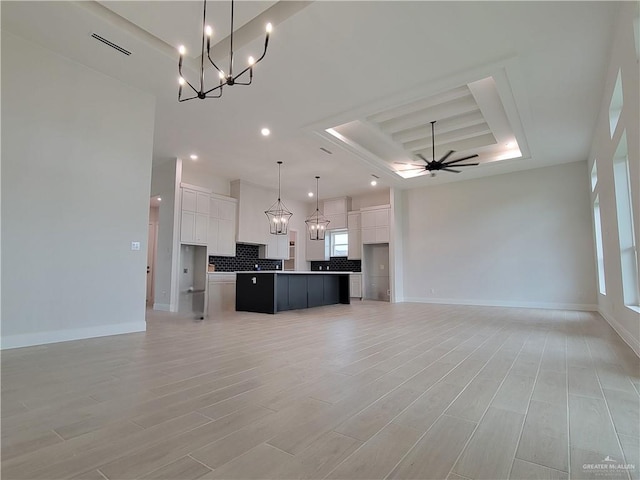 kitchen with a tray ceiling, open floor plan, and white cabinetry