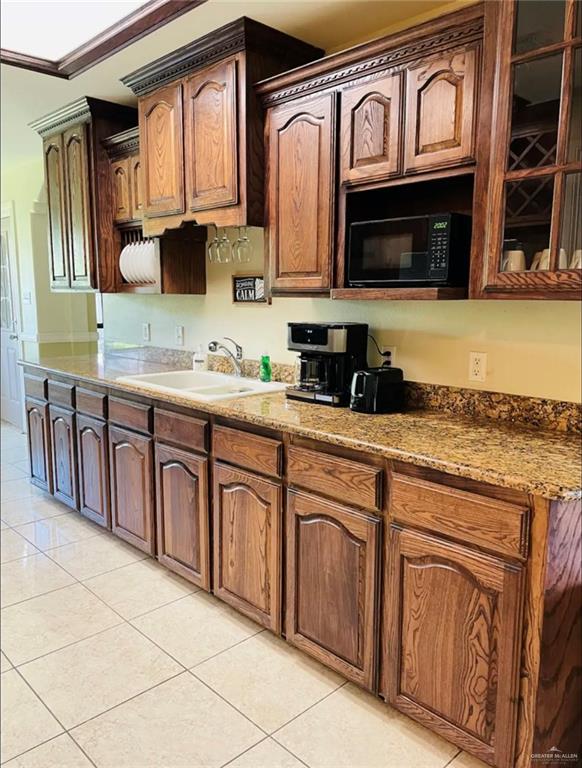 kitchen featuring sink, light tile patterned flooring, and stone countertops