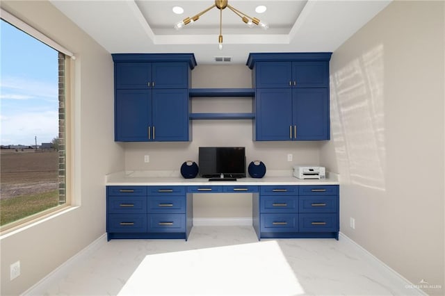 office area featuring a raised ceiling and built in desk