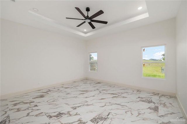 unfurnished room with ceiling fan and a raised ceiling