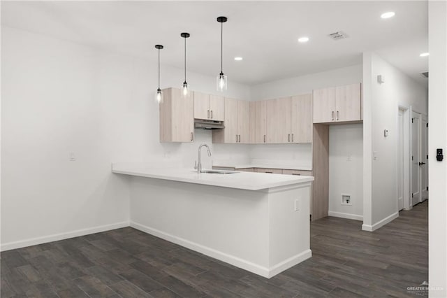 kitchen featuring kitchen peninsula, dark wood-type flooring, sink, light brown cabinets, and hanging light fixtures