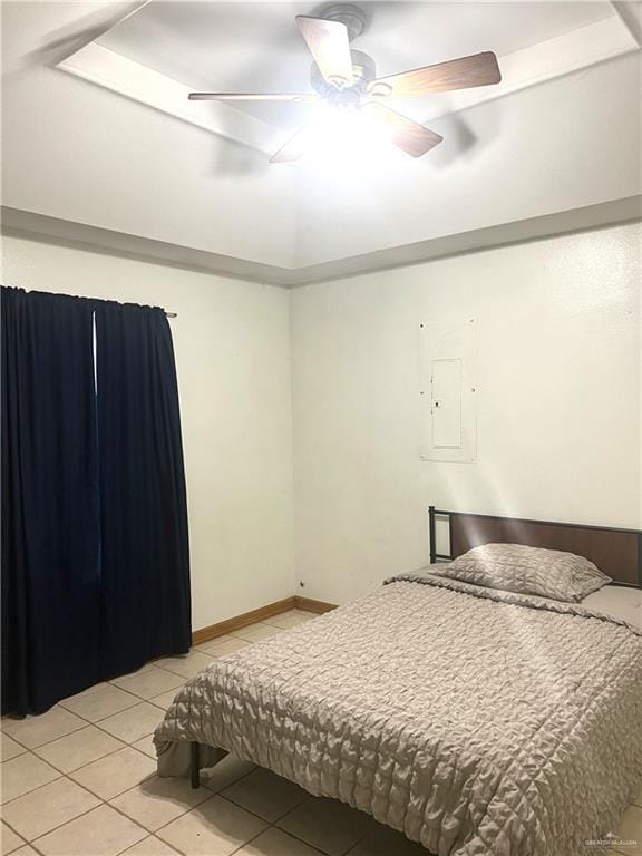 bedroom featuring ceiling fan, a raised ceiling, and light tile patterned floors