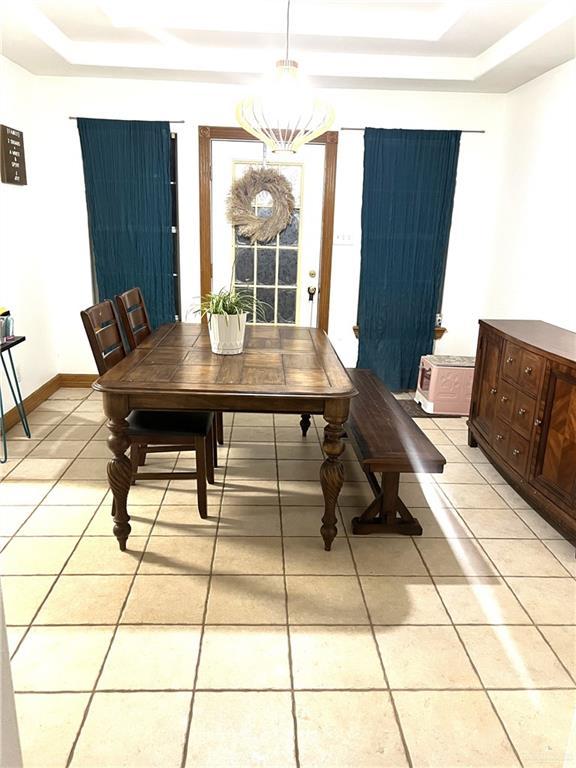 dining space with light tile patterned flooring and a raised ceiling