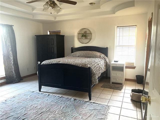 bedroom featuring light tile patterned flooring, ceiling fan, and a tray ceiling