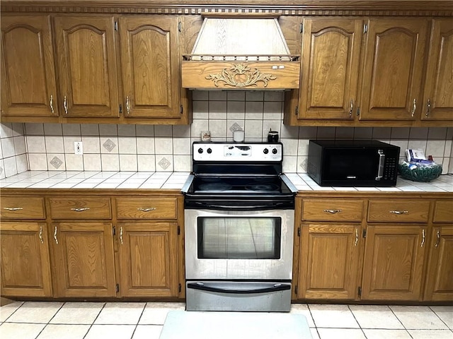 kitchen with stainless steel range with electric stovetop, light tile patterned floors, and backsplash