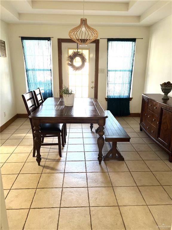 tiled dining space featuring a wealth of natural light and a tray ceiling