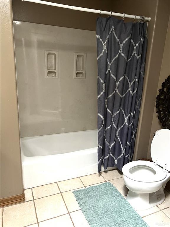 bathroom with tile patterned flooring, shower / tub combo, and toilet