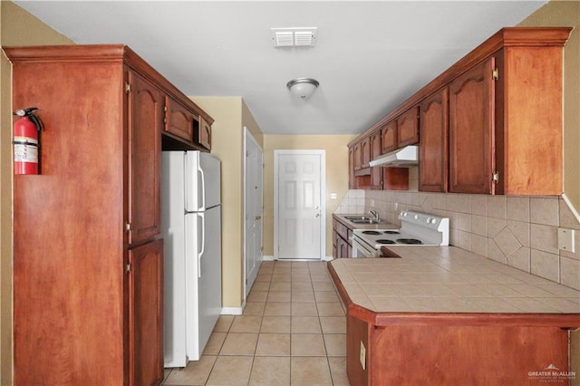 kitchen with tile countertops, light tile patterned floors, visible vents, white appliances, and under cabinet range hood