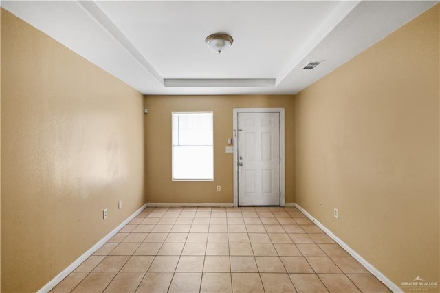 unfurnished room with light tile patterned floors, a raised ceiling, visible vents, and baseboards