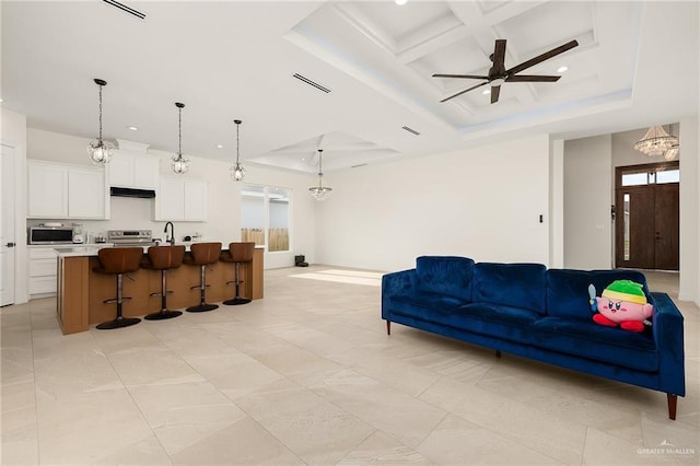 living room with a raised ceiling, a wealth of natural light, coffered ceiling, and ceiling fan