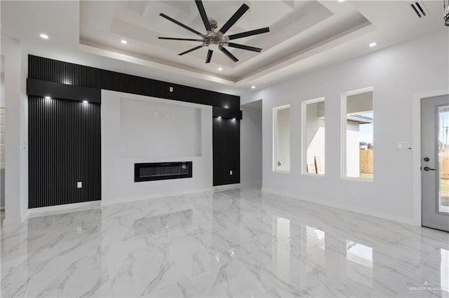 unfurnished living room featuring ceiling fan and a tray ceiling