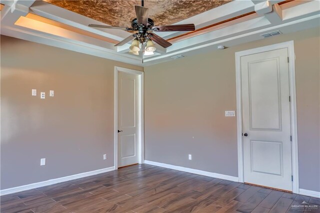 empty room featuring dark hardwood / wood-style floors, ceiling fan, and a tray ceiling