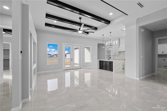 unfurnished living room featuring french doors, sink, beam ceiling, and ceiling fan with notable chandelier