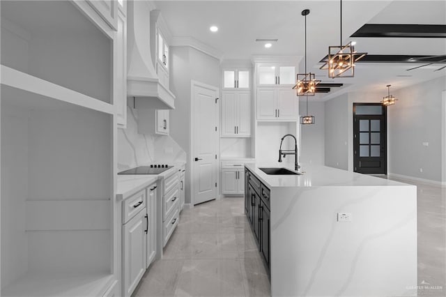 kitchen with an island with sink, custom range hood, sink, and white cabinets