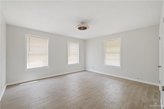 unfurnished room featuring baseboards, plenty of natural light, and wood finished floors