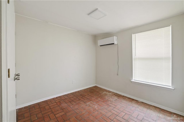 empty room with brick floor, a wall mounted air conditioner, baseboards, and plenty of natural light