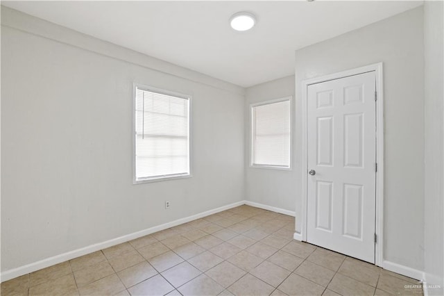 empty room featuring light tile patterned floors and baseboards