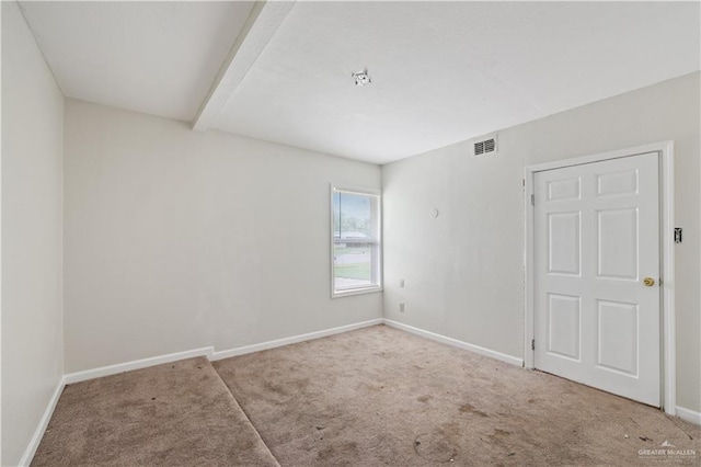 carpeted spare room with visible vents, baseboards, and beam ceiling