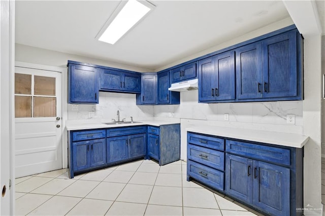 kitchen featuring under cabinet range hood, decorative backsplash, a sink, and light tile patterned floors