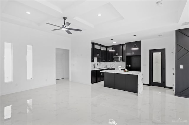 kitchen with stainless steel microwave, coffered ceiling, dark cabinets, and open floor plan