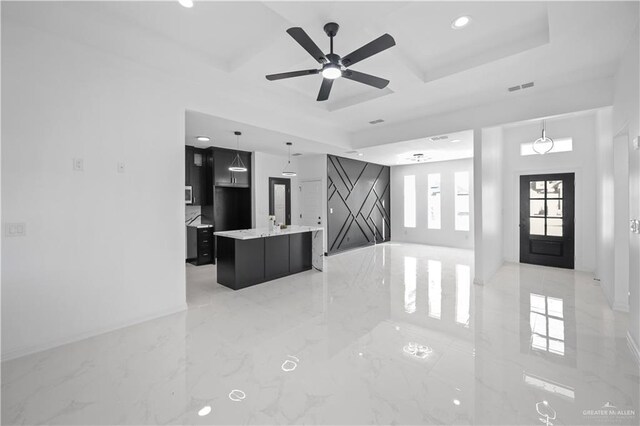 kitchen featuring light stone counters, a center island, sink, and hanging light fixtures