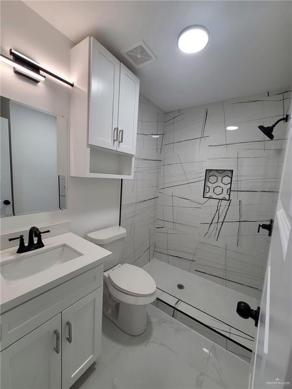 bathroom with vanity, a tile shower, and toilet