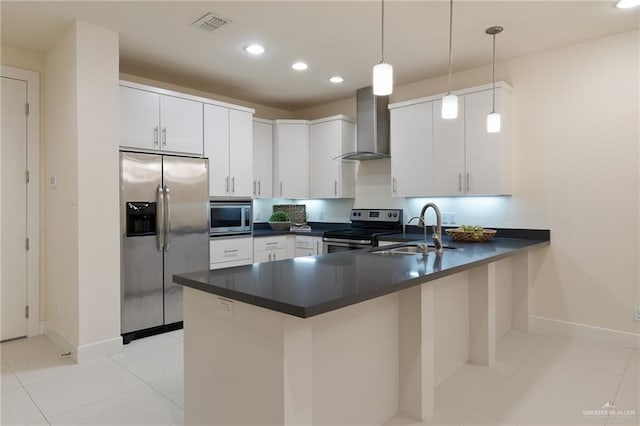 kitchen with stainless steel appliances, sink, wall chimney range hood, white cabinets, and hanging light fixtures