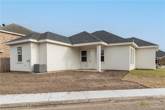 ranch-style home with cooling unit, fence, roof with shingles, and stucco siding