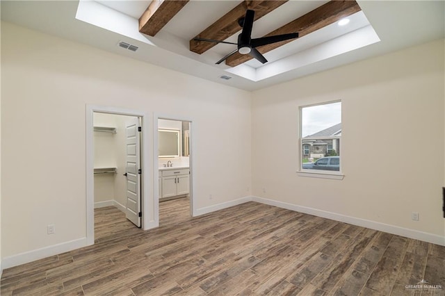 unfurnished bedroom with baseboards, beam ceiling, and wood finished floors