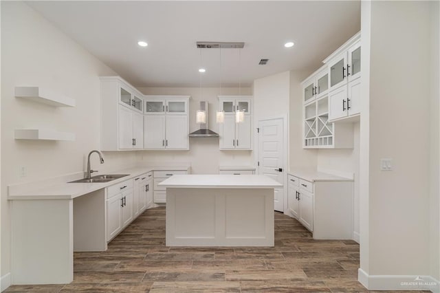 kitchen featuring a sink, open shelves, a kitchen island, wall chimney range hood, and dark wood-style flooring