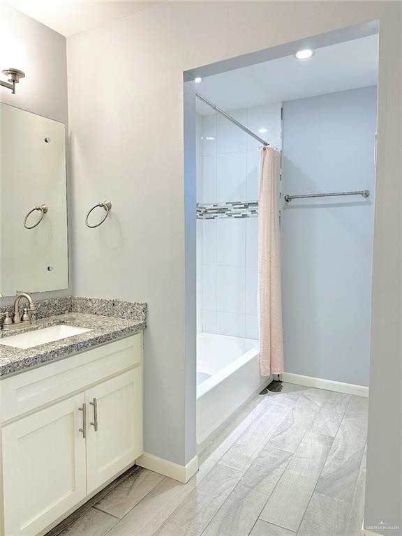 bathroom with shower / bath combination with curtain, vanity, and baseboards