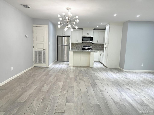 kitchen featuring tasteful backsplash, appliances with stainless steel finishes, open floor plan, and light wood-style flooring