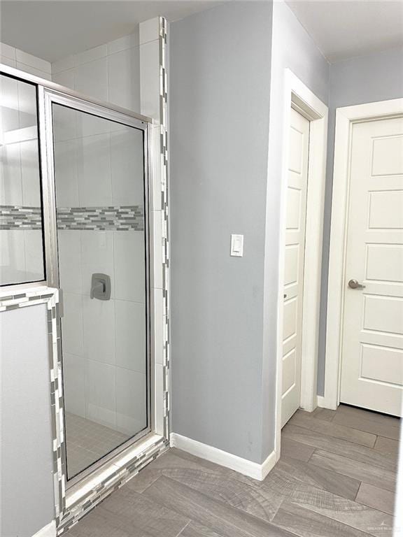 full bath featuring baseboards, a shower stall, and wood tiled floor