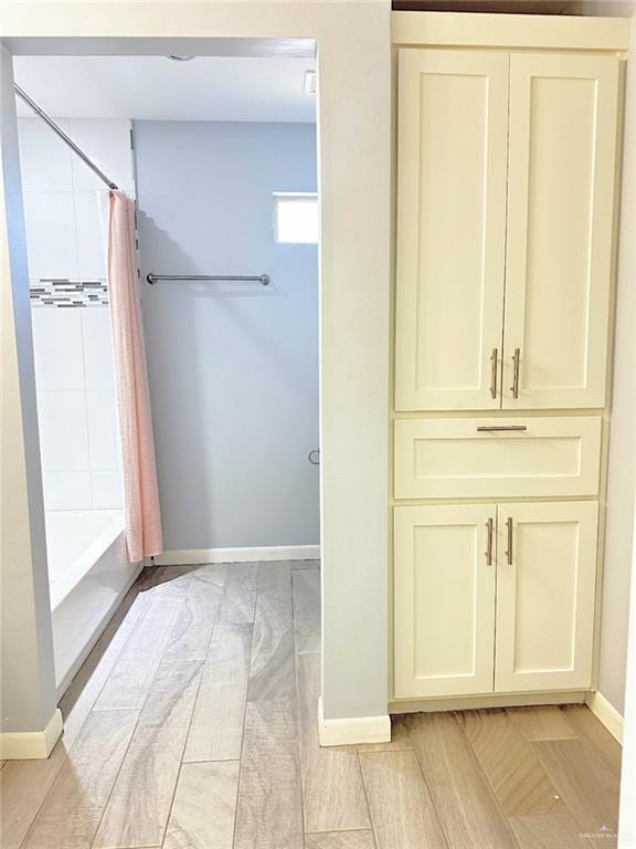 bathroom featuring shower / bathtub combination with curtain and baseboards