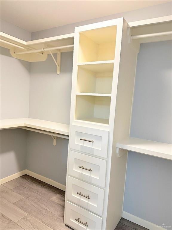 spacious closet featuring light wood finished floors and built in study area