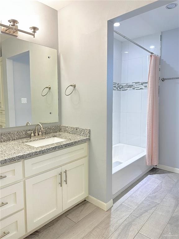 bathroom with baseboards, shower / bath combo with shower curtain, and vanity