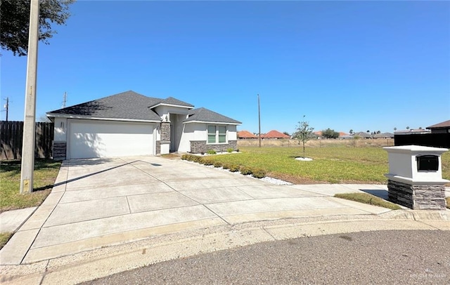 prairie-style house with an attached garage, a shingled roof, fence, concrete driveway, and a front lawn