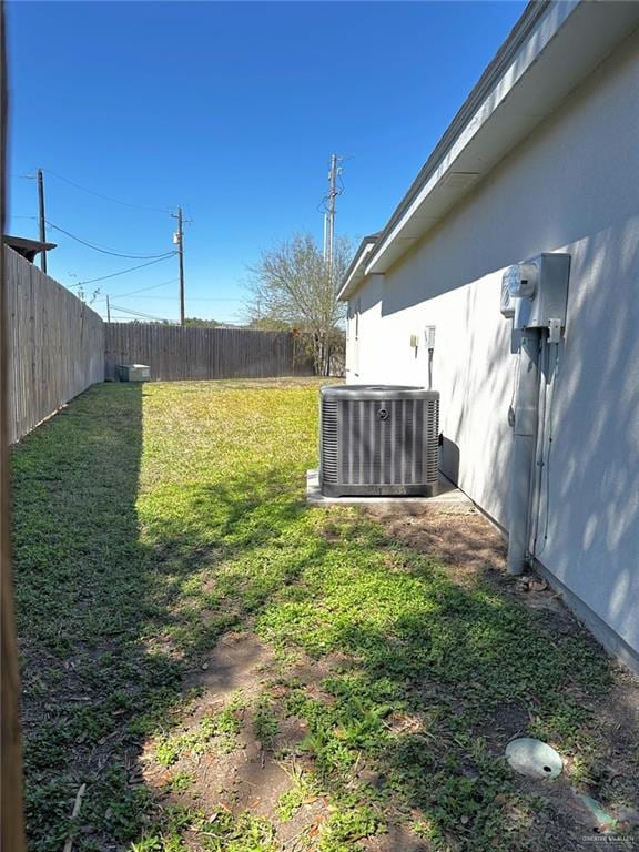 view of yard with a fenced backyard and central AC unit