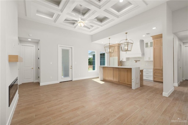 kitchen featuring pendant lighting, a towering ceiling, light wood-type flooring, and a kitchen island