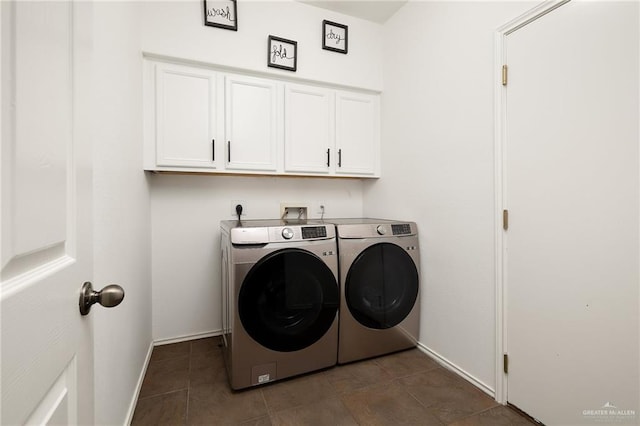 washroom featuring cabinets, washing machine and clothes dryer, and dark tile patterned flooring