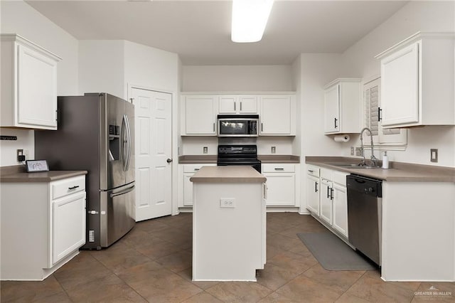 kitchen featuring sink, dark tile patterned floors, appliances with stainless steel finishes, white cabinetry, and a center island