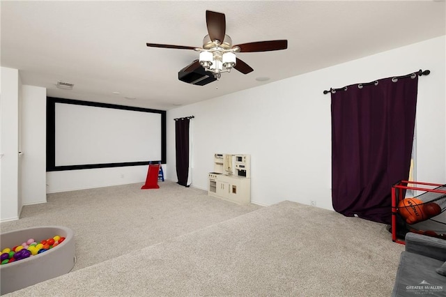 carpeted home theater room with ceiling fan