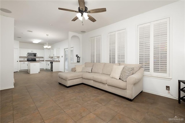 living room featuring ceiling fan with notable chandelier