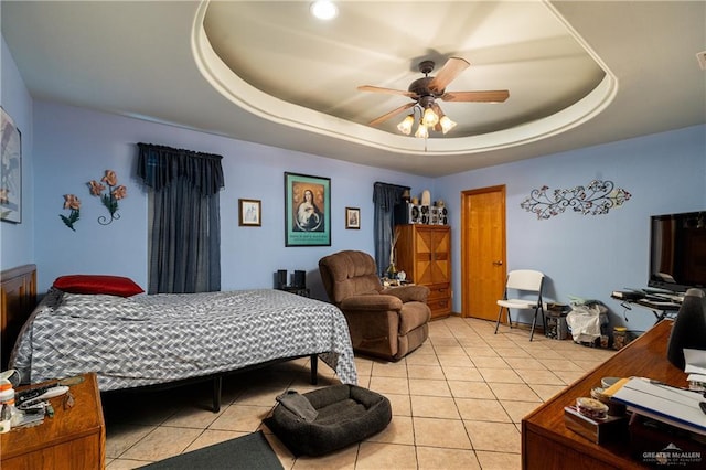 bedroom featuring light tile patterned floors, ceiling fan, and a raised ceiling