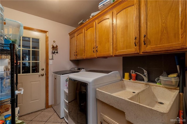 clothes washing area featuring separate washer and dryer, light tile patterned flooring, a sink, and cabinet space