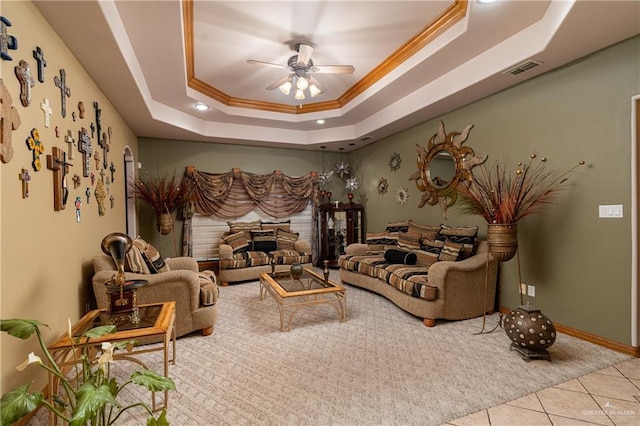 interior space with a ceiling fan, ornamental molding, a tray ceiling, a fireplace, and light tile patterned flooring