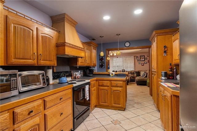 kitchen featuring brown cabinetry, dark countertops, black range with electric stovetop, decorative light fixtures, and premium range hood