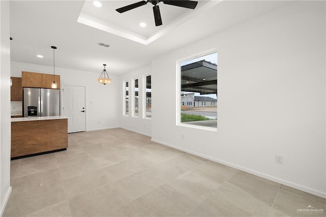 unfurnished living room with a raised ceiling, a ceiling fan, recessed lighting, and visible vents