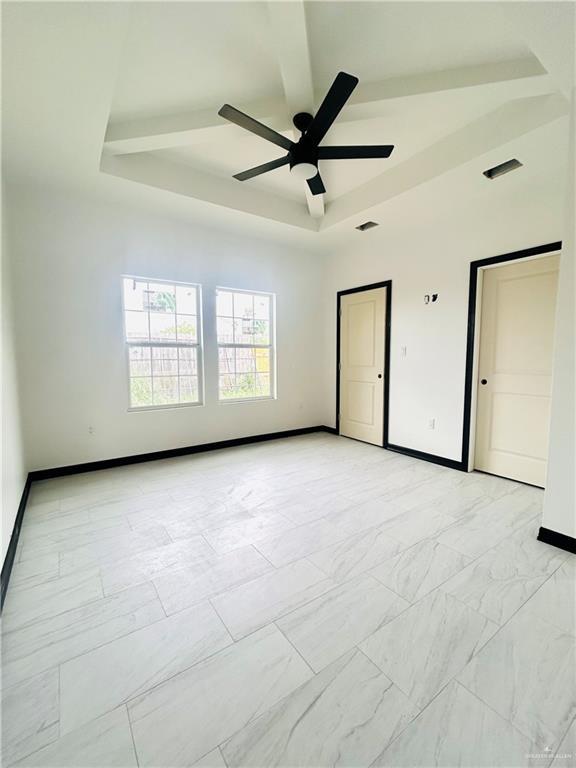 spare room featuring ceiling fan, baseboards, marble finish floor, and a raised ceiling