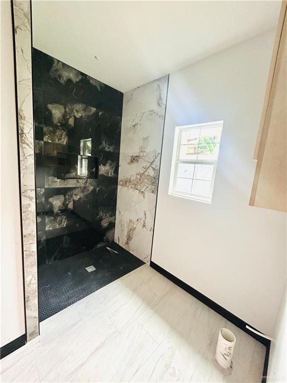 interior space with stone wall, marble finish floor, and a walk in shower